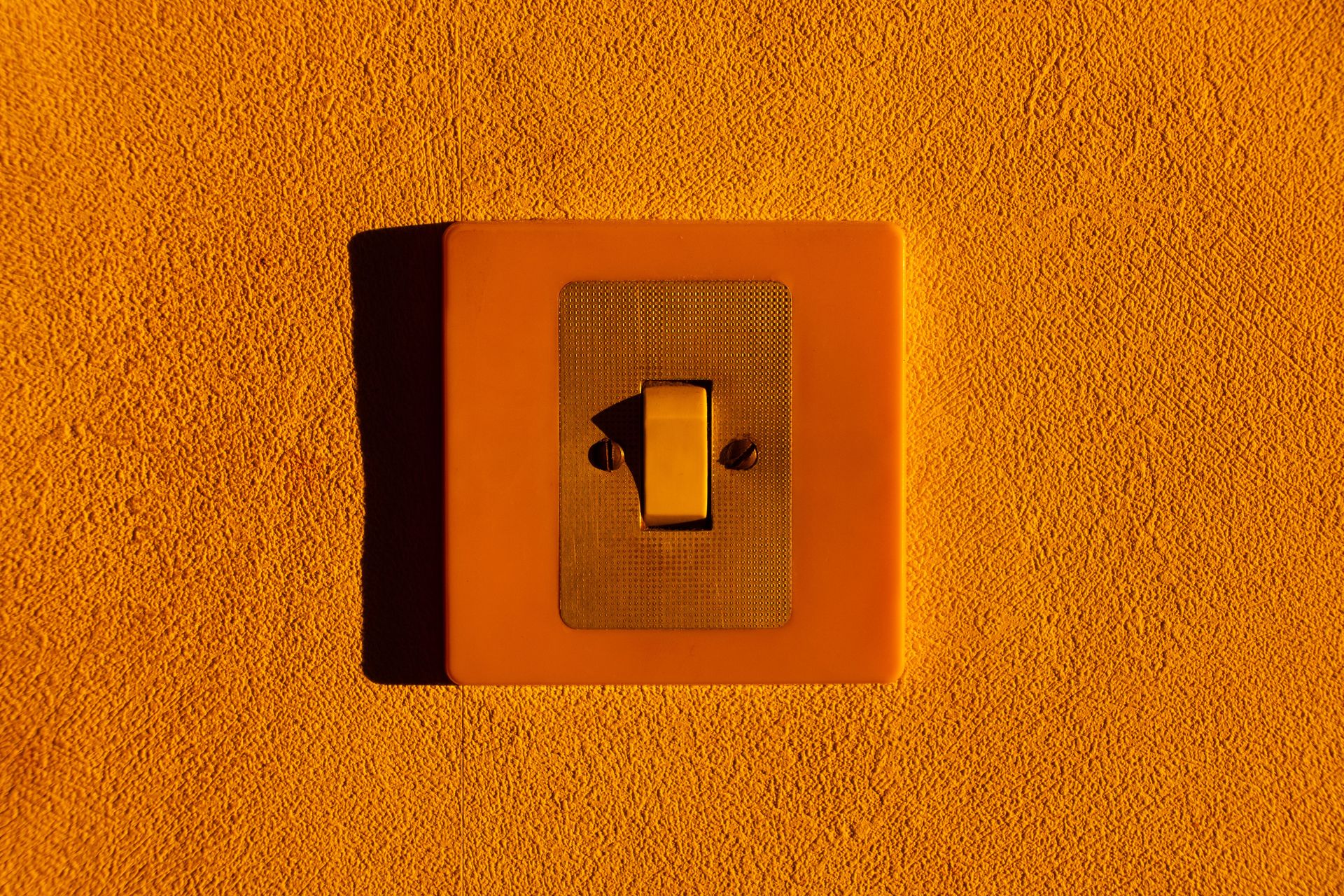 Close-up of a yellow light switch on a textured wall, highlighting minimalism.