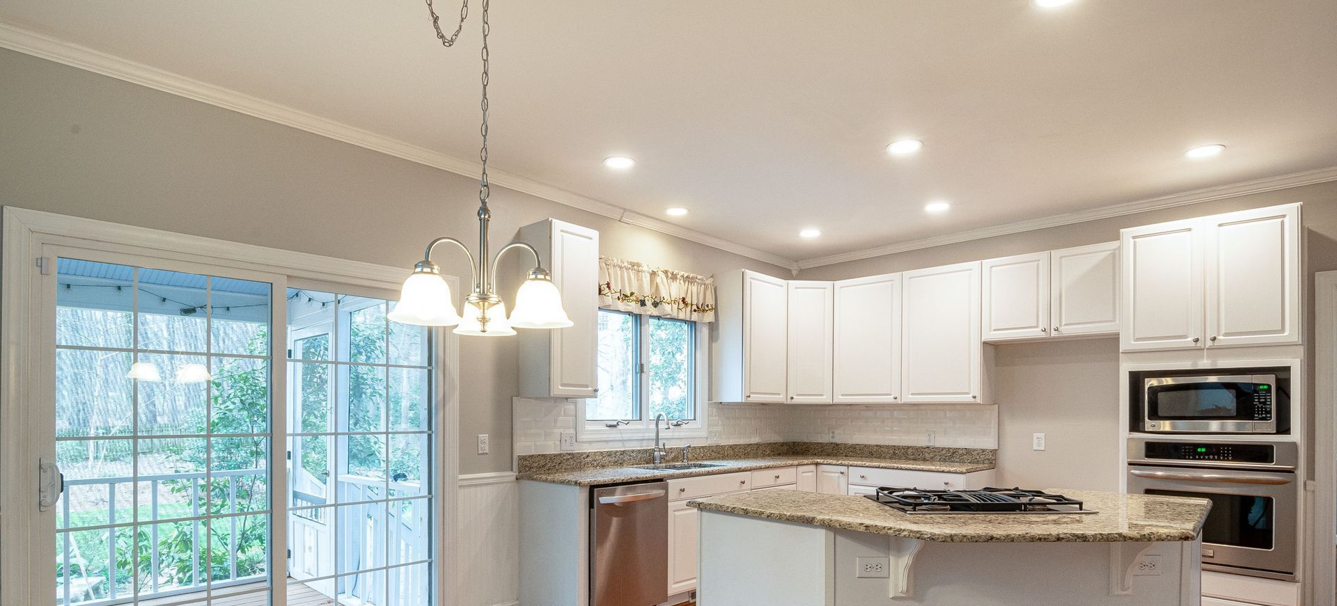 Bright modern kitchen featuring marble island and wooden flooring, ideal for family spaces.